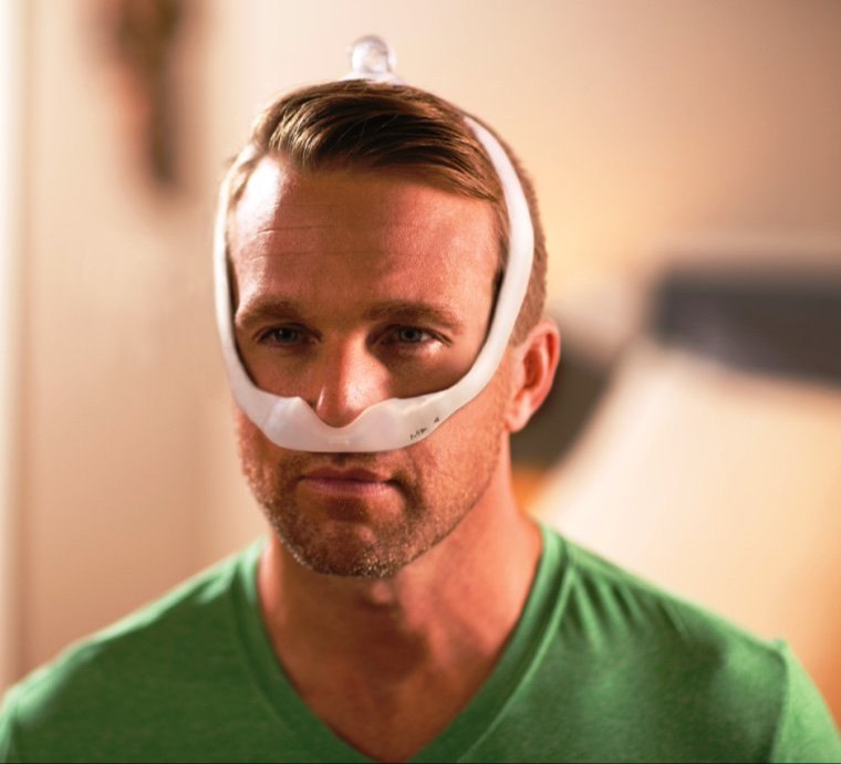 A close-up of a man wearing a Philips Respironics DreamWear nasal mask that fits beneath the nose.