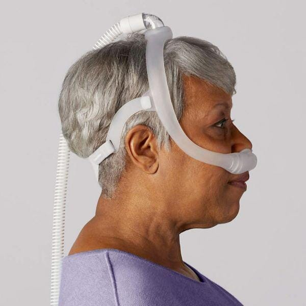 A side view of a woman wearing the Philips Respironics DreamWear under-the-nose nasal mask connected to a CPAP tube.