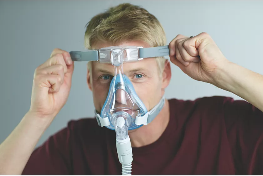 A man adjusting a Philips Respironics Amara Gel Full Face CPAP mask on his face