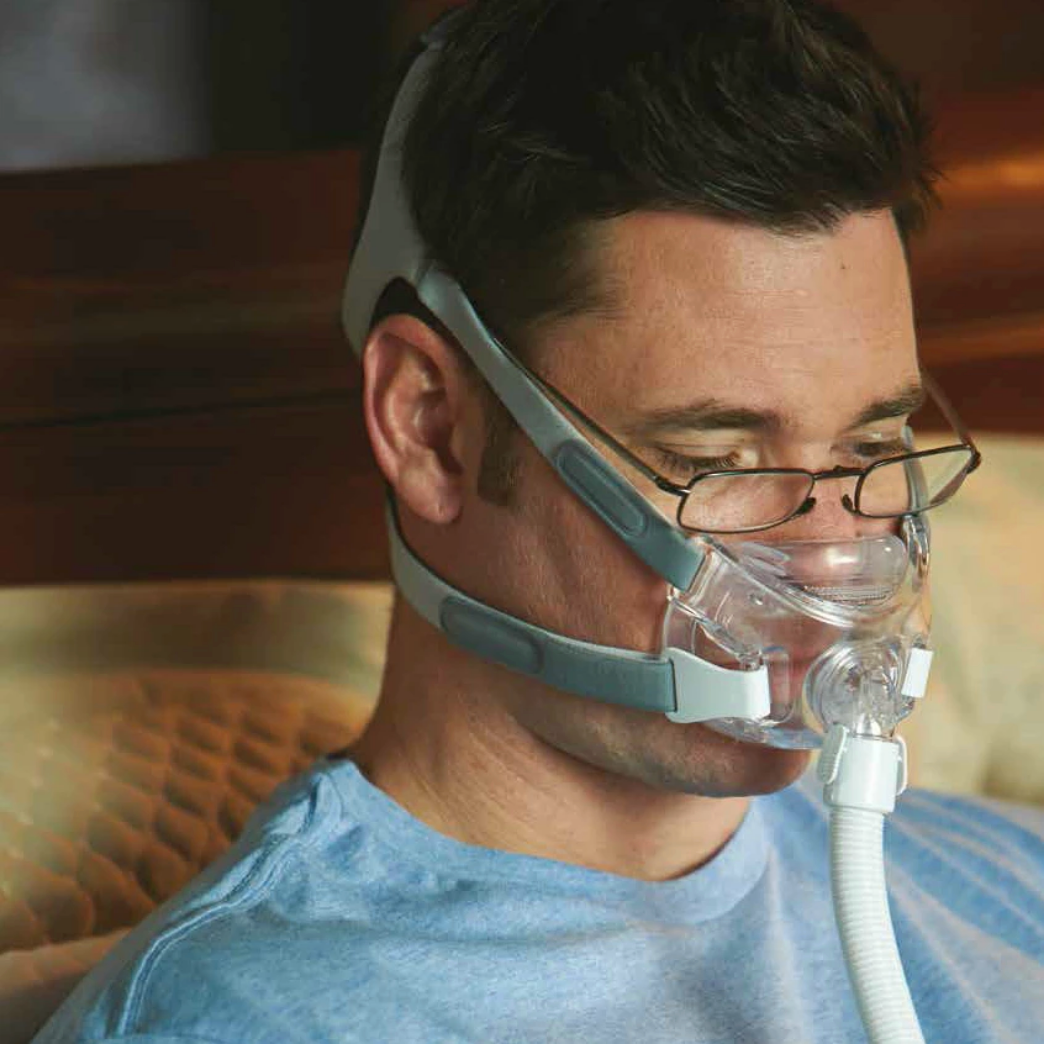 Side view of a man wearing the Philips Respironics Amara View Full Face Mask and his reading glasses.