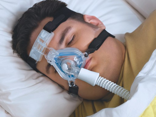 Person wearing a Philips Respironics ComfortGel nasal CPAP mask and hose while sleeping