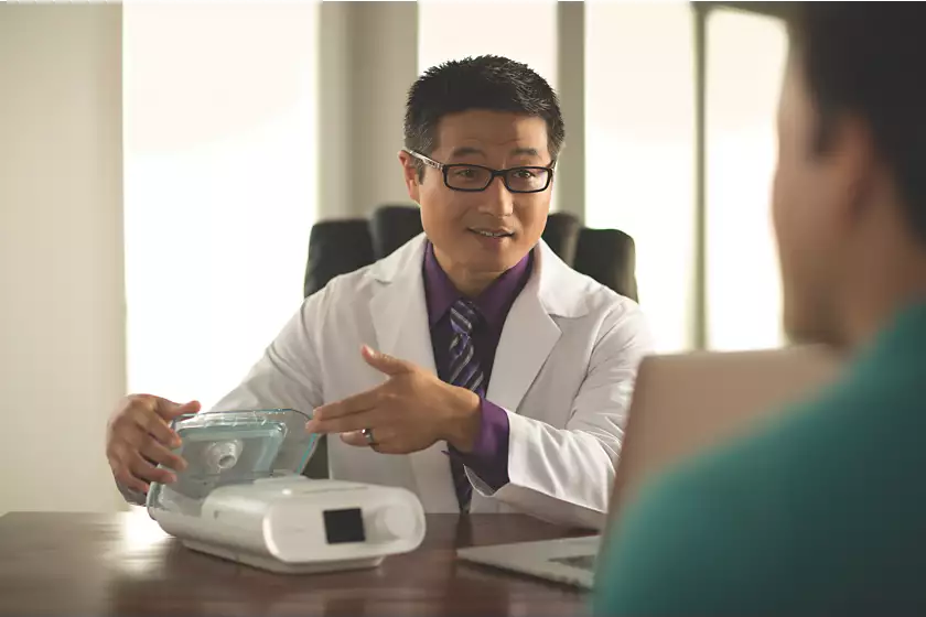 Healthcare provider assisting the patient with a Philips Respironics DreamStation Auto CPAP.