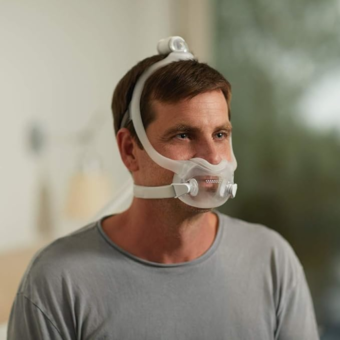 A man wearing a Philips Respironics DreamWear Full Face CPAP mask with headgear, designed for comfortable sleep apnea therapy and a secure fit.