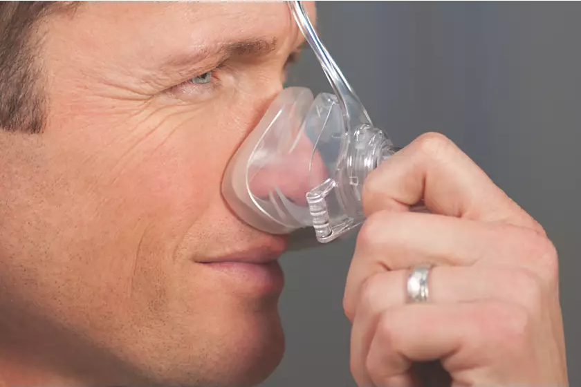 A man presses the Philips Respironics Pico Nasal mask to his face, covering his nose.