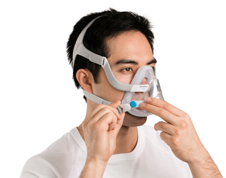 A man wearing the ResMed AirFit F20 full-face mask connects the magnetic clip.